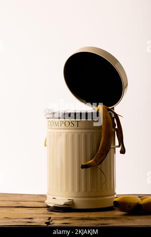 Vertikales Bild von Bananenhaut, die aus dem Kompostierbehälter in der offenen Küche hängt Stockfoto