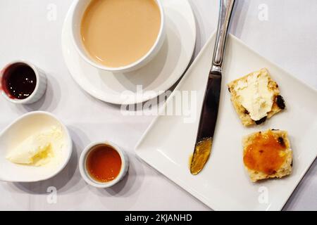 Tee und ein Rosinengebäck, serviert mit einer Auswahl an Marmelade und aufgemacht mit Clotted Cream, beim Nachmittagstee in Hongkong. Stockfoto