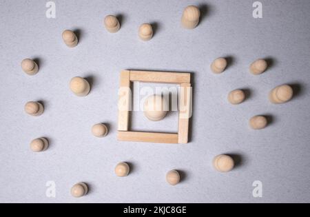 Mobbing, Belästigung am Arbeitsplatz und Einsamkeit. Holzfiguren auf dem Schreibtisch Stockfoto