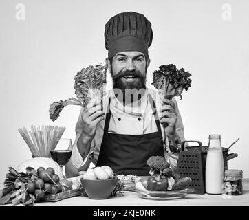 Kochen Sie mit einem Lächeln in burgunderner Uniform am Küchentisch Stockfoto