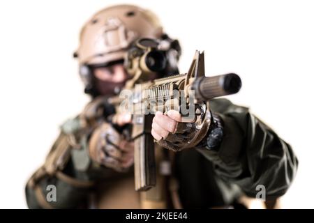 Ein Soldat mit taktischer Ausrüstung zielt mit Scharfschützengewehr auf den Feind. Oberflächlicher Fokus auf Gewehr. Isoliert auf weißem Hintergrund. Stockfoto