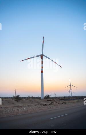 Licht vor der Dämmerung am Wüstenhimmel mit Strom erzeugenden Windmühlen, die umweltfreundliche Energie für den Verbrauch durch die Einheimischen erzeugen Stockfoto