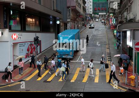 Fußgänger überqueren die Cheung Hong Street an der Kreuzung von Kings Road, North Point, bei leichtem Regen, Hongkong, 24. November 2022 Stockfoto