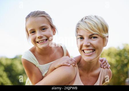 Eine Tochter ist ein kleines Mädchen, das zu deiner besten Freundin heranwächst. Ein verkürztes Porträt einer glücklichen Mutter, die ihre kleine Tochter mit dem Huckepack reitet. Stockfoto