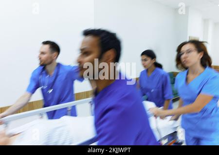 Bewegungsunschärfe-Effekt im Krankenhausnotfall mit Patient auf Trage und medizinischem Personal, das ihn schiebt. Die Arbeit des Notfallteams Stockfoto