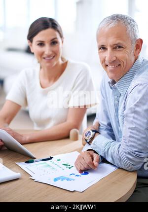 Die Zukunft des Unternehmens sieht vielversprechend aus. Zwei erfolgreiche Geschäftskollegen, die gemeinsam ein Dokument durchgehen. Stockfoto