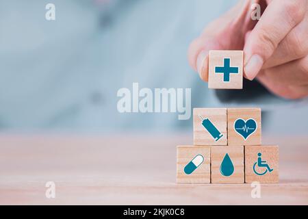 Geschäftsmann wählt ein Emoticon Symbole Gesundheitswesen medizinisches Symbol auf Holzblock , Gesundheitswesen und medizinische Versicherung Konzept Stockfoto