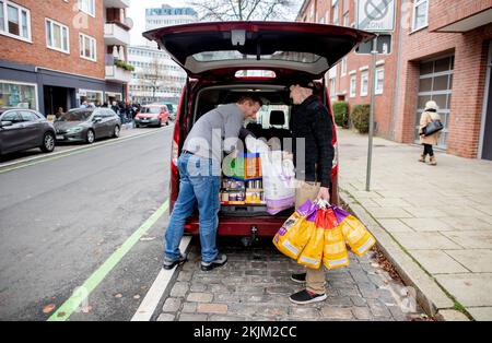 Bremen, Deutschland. 18.. November 2022. Stefan Evers (l), Vorsitzender der Bremer Tiertafel, und Tim Vieregge, Freiwilliger bei der Bremer Tiertafel, entladen Lebensmittelspenden aus einem Auto. Die Zahl der bedürftigen Haustierbesitzer und der Bedarf an Heimtierfutter und Sachspenden sind in diesem Jahr stark gestiegen. (Dpa: "Die Nachfrage in Tiertafeln in Niedersachsen und Bremen steigt") Kredit: Hauke-Christian Dittrich/dpa/Alamy Live News Stockfoto
