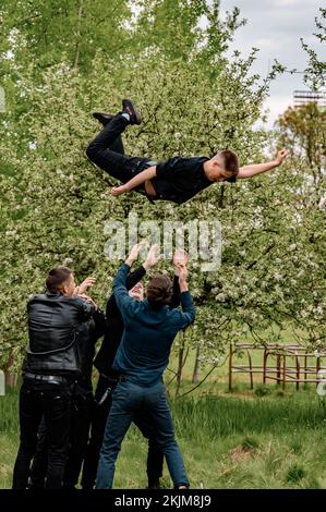 Ivano-Frankivsk, Ukraine, 15. Mai 2021: Ein Gruppenfoto von Jungen mit Klassenkameraden, die einen Jungen nach oben werfen. Stockfoto