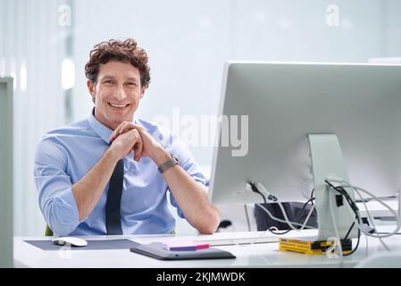 Er lässt das Geschäft einfach aussehen. Ein junger Geschäftsmann, der an seinem Schreibtisch sitzt. Stockfoto