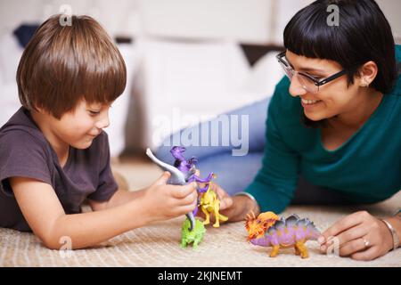 Ein bisschen Spaß mit Dinosauriern. Eine Mutter und ihr Sohn, die mit Spielzeugdinosauriern spielen. Stockfoto