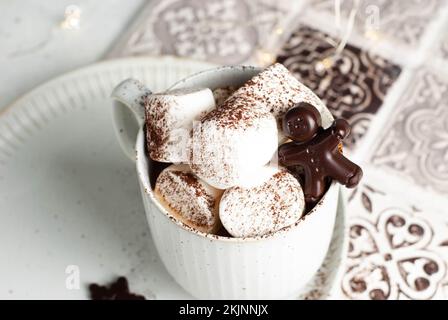 Heißgetränketasse mit Marshmallow und Schokoladen-Lebkuchenmann. Weihnachtskreationen Stockfoto