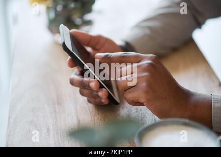 Hand, Tisch und Telefon mit einem Mann, der im Internet surft oder einem mobilen Kontakt Textnachrichten schreibt, während er sich entspannt. Hände, Handy und afroamerikanischer Mann Stockfoto