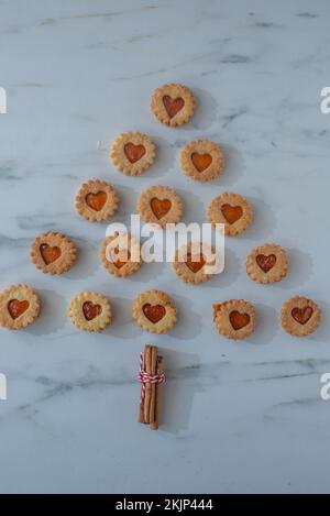 Süße hausgemachte linzer weihnachtskekse gefüllt mit Aprikosenmarmelade auf einem Tisch Stockfoto