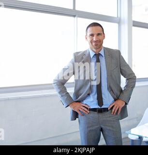 Er ist ein Großunternehmen. Ein gutaussehender Geschäftsmann, der in seinem Büro steht. Stockfoto