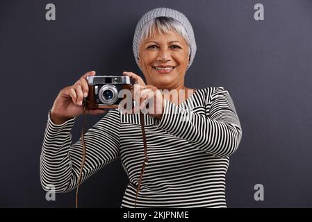 Der nächste große Fotograf. Porträt einer erwachsenen Frau, die eine Kamera in einem Studio hält. Stockfoto