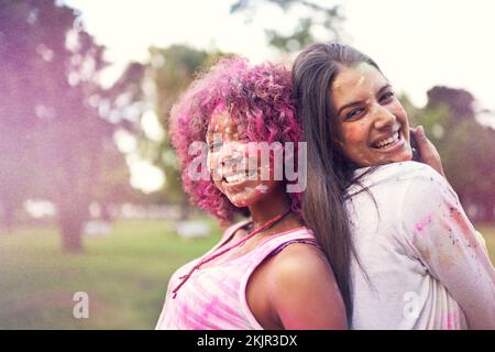 Leben in Farbe. Porträt von zwei Freunden, die Spaß auf einem Farbfestival haben. Stockfoto