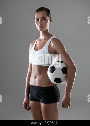 Du könntest einen Ball von den bauchmuskeln abprallen. Studiofoto einer jungen Frau mit einem Football. Stockfoto
