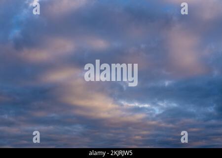 Wunderschöner Sonnenuntergang- oder Sonnenaufgangshimmel, der dunkelblaue und blassrosa Wolken erhellt. Wolkiger Himmel, um auf Ihren Fotos zu überlagern. Stockfoto