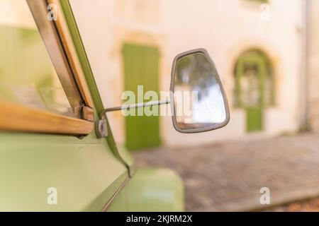 Nahaufnahme des Seitenspiegels eines grünen Oldtimers auf verschwommenem Hintergrund Stockfoto