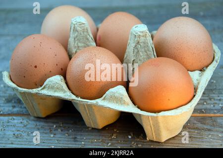 Sechs braune Hühnereier in einer Schachtel auf einem Holztisch Stockfoto