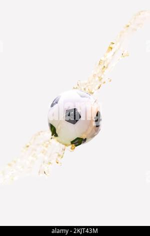 Fußball mit Bierspritzer auf weißem Hintergrund. Konzept von Fußball- und Fussballfans und Meisterschaft. Stockfoto