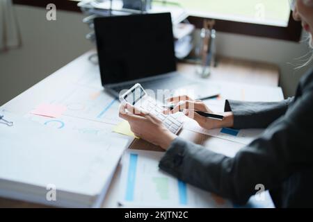 Buchhalter, asiatische Wirtschaftsprüfer verwenden Rechner und Computer, um die jährlichen Steuerbudgets zu überprüfen, um Informationen an das IRS zu übermitteln. Stockfoto