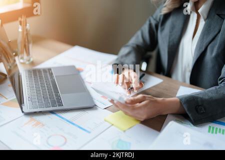 Buchhalter, asiatische Wirtschaftsprüfer verwenden Rechner und Computer, um die jährlichen Steuerbudgets zu überprüfen, um Informationen an das IRS zu übermitteln. Stockfoto