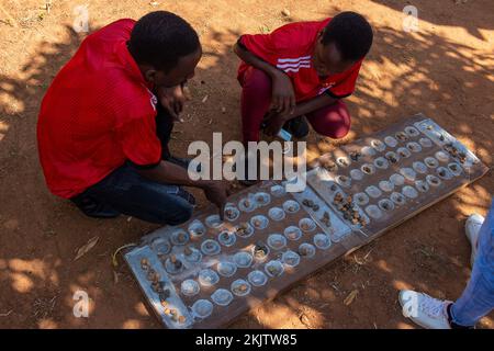 Jungs, die traditionelles mancala-Spiel mit kleinen Steinen spielen Stockfoto