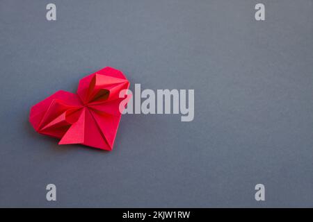 Rotes Papier Herz Origami isoliert auf einem weißen grauen Hintergrund. Valentinskarte Stockfoto
