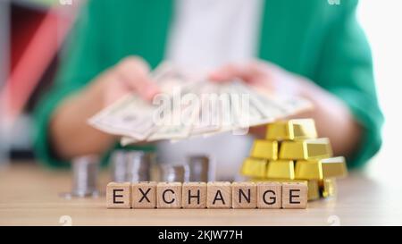 Frau mit Banknoten, Bargeld und Goldbarren, Münzen auf dem Tisch Stockfoto