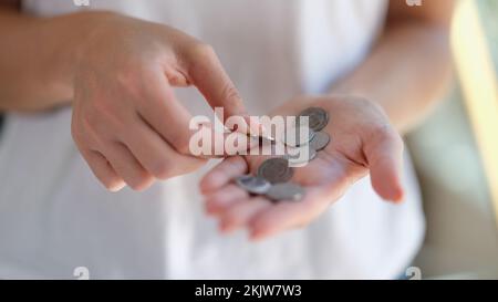 Weibliche Hände halten und zählen Silbermünzen Stockfoto