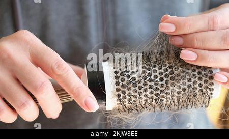 Weibliche Hände halten den runden Kamm mit Haarausfall Stockfoto