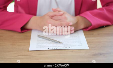Die Geschäftsfrau sitzt am Tisch und legt den Vertrag in die Hand Stockfoto