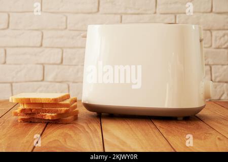 Weißer elektrischer Toaster und Sack mit frischen Brotscheiben. Koch- und Haushaltstechnologien mit Hintergründen Stockfoto