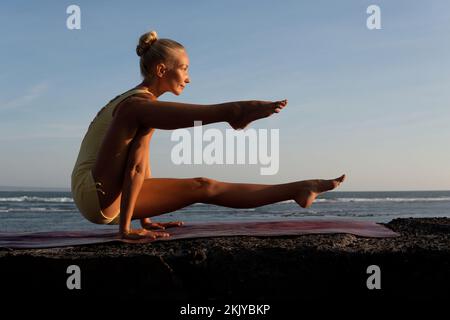 Schöne Frau, die Yoga am Strand macht. bali Stockfoto