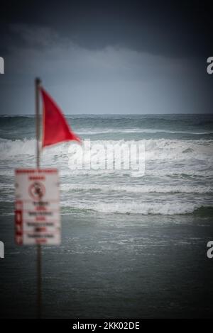 Gefahr Red Flags fliegen am Strand, während raue Meere die Wellen entlang der Küste in Minizan, Frankreich, brechen Stockfoto