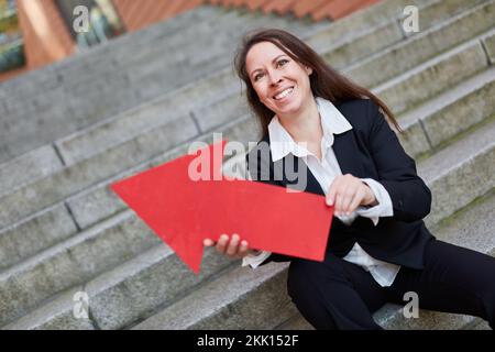 Erfolgreiche Geschäftsfrau mit rotem Pfeilsymbol als Erfolg und Karrieresymbol Stockfoto