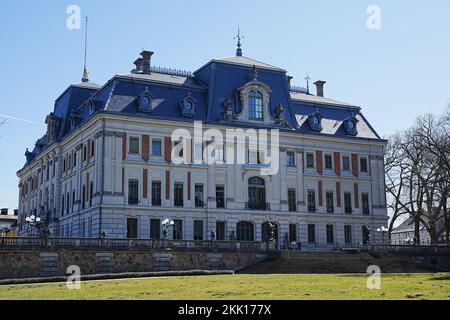 Grasfeld und neobarocker Palast im Park der europäischen Stadt Pszczyna in Polen, klarer blauer Himmel am 2022. Warmen sonnigen Frühlingstag am März. Stockfoto