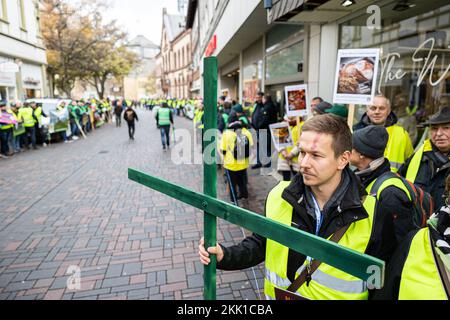 Goslar, Deutschland. 25.. November 2022. Ein Teilnehmer einer menschlichen Bauernkette in der Innenstadt von Goslar hält ein hölzernes Kreuz in der Hand. Die Landwirte möchten ihre Situation mit verschiedenen Maßnahmen während der Konferenz der Umweltminister hervorheben. Kredit: Michael Matthey/dpa/Alamy Live News Stockfoto