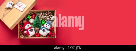 Handgefertigtes Pflegespaket, saisonale Geschenkbox mit Spielzeug, Weihnachtsdekor auf rotem Tisch Personalisierter, umweltfreundlicher Korb für Familie, Freunde, Mädchen für den 24. Dezember Stockfoto