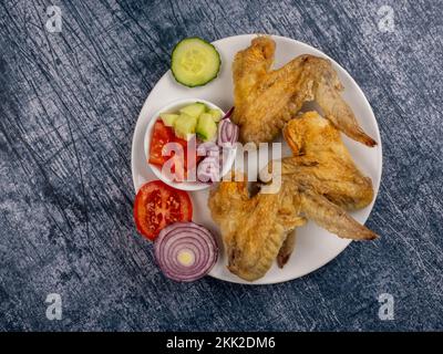 Drei gekochte Hähnchenflügel mit Salat auf einer Granitarbeitsfläche Stockfoto