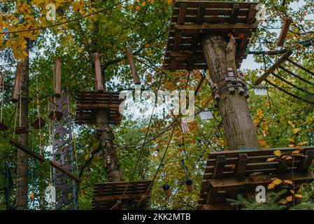 Hochseilgarten Erlebnis Abenteuerbaumpark. Seilbahnkurs in Bäumen. Kletterabenteuer Seilpark. Holzbrücke und hohe Drahtaktivität. Stockfoto