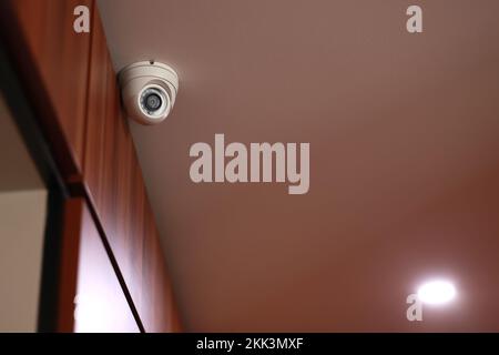 Überwachungskameras im Innenbereich, weiße runde Überwachungskamera oder Überwachungssystem in Bürogebäude, Hotelhalle, Einkaufszentrum an der Decke. Konzept der Surv Stockfoto