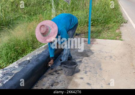 Arbeiter, die den Rand des Fußwegs mit freiliegendem Zuschlagstoff putzen Stockfoto