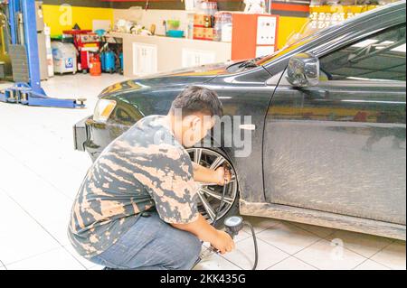 Techniker, der die Luft am Autorad nach der Reifenreparatur in der Werkstatt füllt. Stockfoto