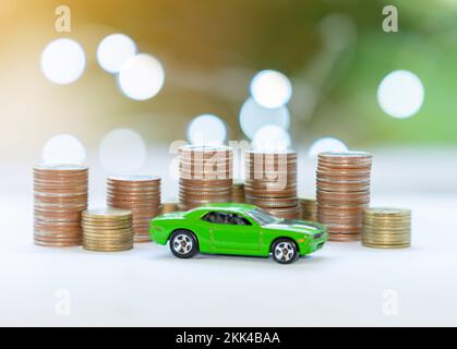 Münzstapel und umweltfreundliches Auto – so sparen Sie Geld für ein Auto mit unscharfem Hintergrund. Stockfoto