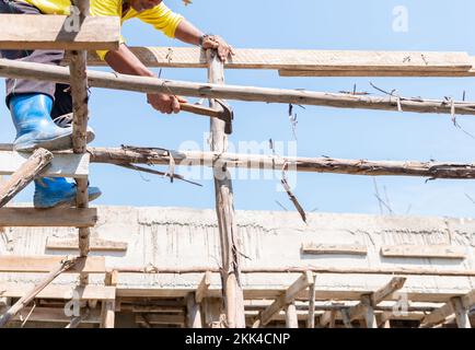 Arbeiter Schlug Nagel Auf Holzstiel Für Stütze Zweite Etage Auf Baustelle. Stockfoto