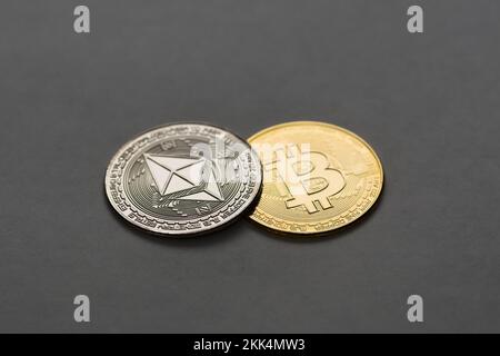 Physikalische Bitcoin- und Ethereummünzen auf dunkelgrauem Hintergrund. Digitale Währung, Kryptowährung, Blockchain-Technologie-Konzept. Stockfoto