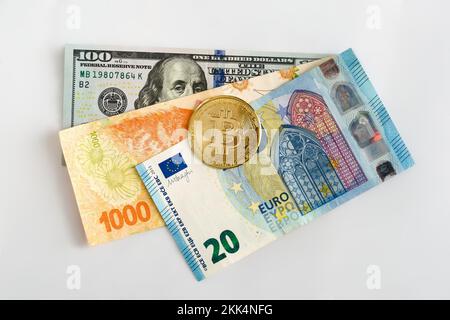 Physische Bitcoin über hundert US-Dollar, zwanzig Euro und tausend argentinische Pesos-Scheine. Kryptowährung, globales Finanzkonzept. Stockfoto